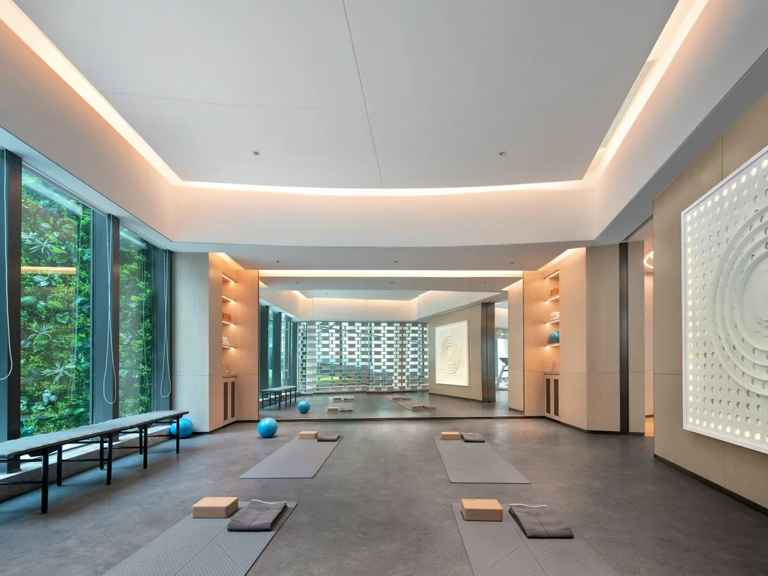 Sala de yoga vacía con esterillas extendidas sobre el suelo, bloques colocados al lado y luz natural entrando por un ventanal lateral.
